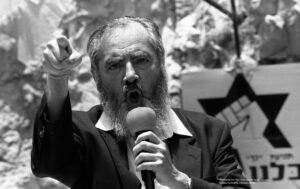 Rabbi Meir Kahane yells into a mic with his finger in the air